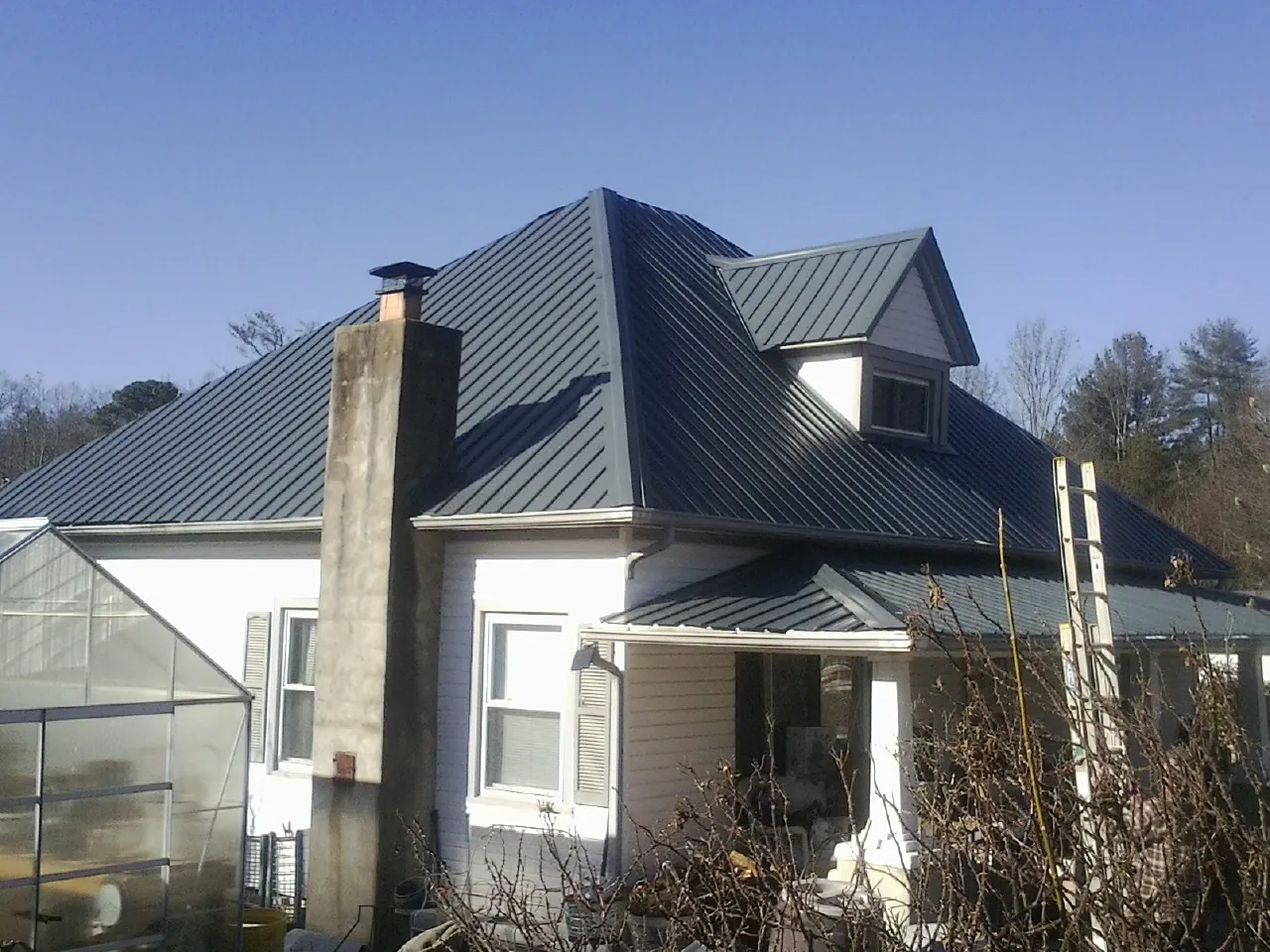 Dark blue standing seam metal roof on a white farmhouse with dormer — Slate & Tile Roof Repair by Roofing Brothers in Constable